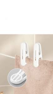 Close-up of white plastic clothes peg with wavy non-slip grip holding a pink towel