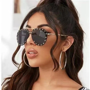 Close-up of black aviator sunglasses with silver studs and large metallic hoop earrings