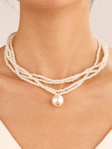 Detail shot of multi-layer pearl necklace with large pendant on model's neck
