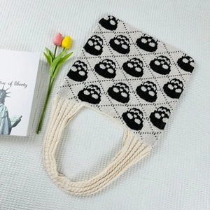 Detail view of knitted handbag featuring black and white skull jacquard pattern and texture