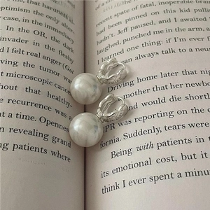 Detail of S925 sterling silver pearl drop earrings placed on an open vintage book page