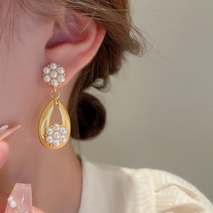 Detail of vintage flower earrings with pearl drop pendant in gold metallic finish