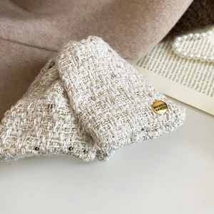 Detail of tweed bow hair claw with gold threads and engraved metal believe buckle
