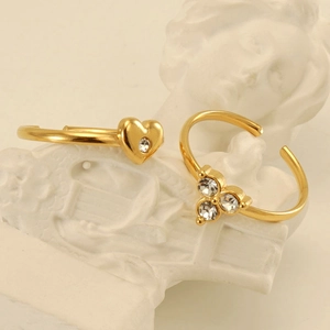 Anelli in acciaio dorato con zircone a cuore e fiore su una statua bianca classica