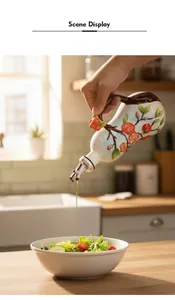 Detail of hand-painted ceramic oil dispenser with persimmon motif pouring oil into a bowl