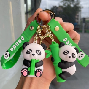 Close-up of cute cartoon panda keychains with green silicone strap and bamboo detail