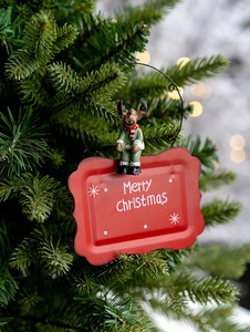 Detail of a red metal Merry Christmas door sign with a green reindeer figure on a tree