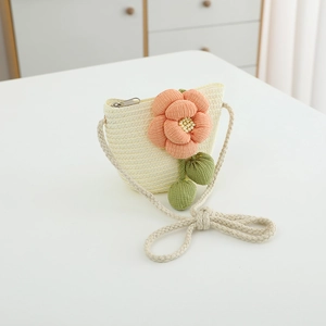 Nahaufnahme einer cremefarbenen Kinder-Strohtasche mit dekorativen Stoffblumen