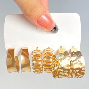 Three pairs of gold-colored geometric earrings with smooth, spiral, and hammered textures