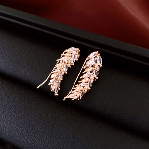Macro shot of gold wheat ear earrings featuring sparkling zircons and delicate pearls