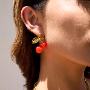 Close-up of 18K gold plated stainless steel cherry drop earrings worn by a model