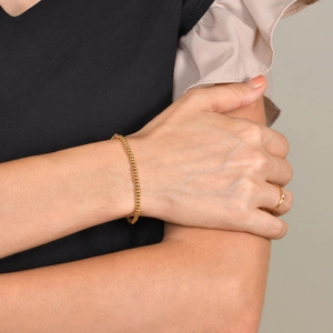 Close-up of a minimalist gold beaded stainless steel bracelet on a woman's wrist