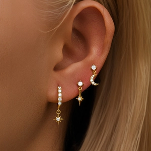 Detailed view of gold plated earrings featuring star and moon charms with sparkling crystals