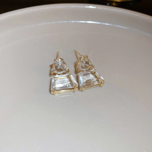Minimalist geometric S925 earrings with gold frames and clear crystals on a ceramic dish