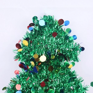 Close-up of a green tinsel Christmas tree topper with vibrant colorful round sequins