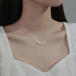 Minimalist silver choker necklace with five elegant white pearls on a delicate chain