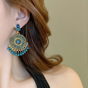 Close-up of bohemian water drop earrings with blue rhinestones and fringe on model