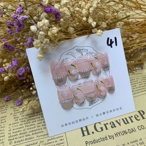 Detail of handmade press-on nails with lily of the valley and pearl accents
