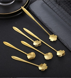 Close-up of golden flower-shaped stainless steel dessert spoons on a dark surface