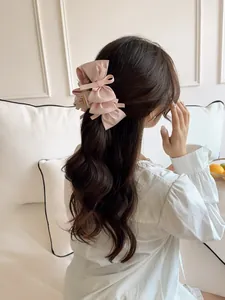 Close-up of a pink satin bow hair claw clip styled on a woman's wavy hair
