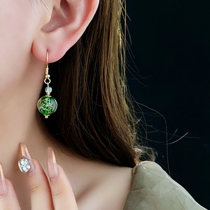 Close-up of green glass bead earrings with gold flakes on female model neck