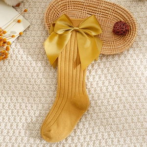 Détail de chaussettes hautes bébé en maille de coton jaune gingembre à gros noeud