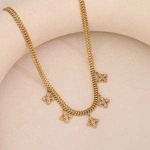 Close-up of golden clover necklace with sparkling zircon stones on woven chain links