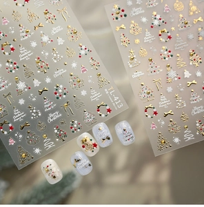 Macro shot of 5D gold embossed Christmas nail art stickers with tree and bell designs