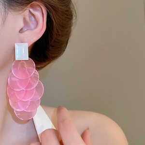 Close-up of long tassel shell earrings with layered pink translucent discs and white studs