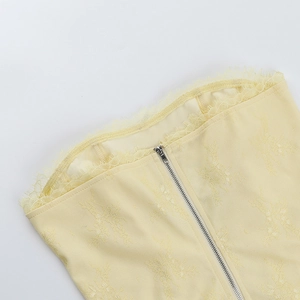 Détail macro de la bordure en dentelle florale jaune et du zip métallique sur le haut