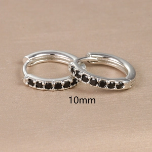 Close-up of 10mm silver hoop earrings with black zircon stones on a textured surface