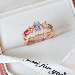 Close-up of rose gold double-layer ring with multicolor gemstones and white zircons