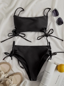 Flat lay of black high-waisted bikini set with side drawstring details on white fabric