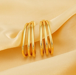 Macro detail of triple-layered 18K gold plated stainless steel hoops on satin fabric