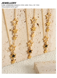 Close-up of gold star pendants with black enamel on a beige stone display base