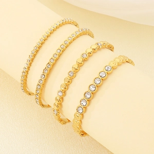 Détail de bracelets en acier titane doré avec zircons incrustés sur support d'exposition