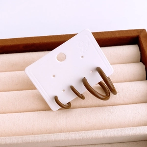 Detail view of brown geometric hollow hoop earrings displayed on a white jewelry card