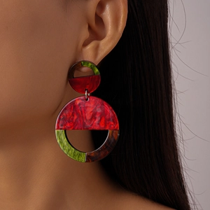 Close-up of geometric acrylic earrings featuring dark red marble and olive green resin