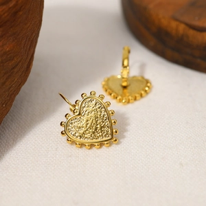 Detailed close-up of vintage heart earrings with hammered texture and beaded gold edge