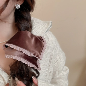 Detail view of a velvet scrunchie with lace trim styled on a braided hairstyle