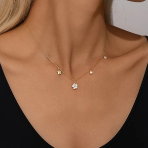 Detail of S925 silver gold necklace with star, floral, and pearl pendant on model
