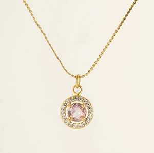 Macro detail of 18K gold necklace with a round pink gemstone pendant and zircon accents