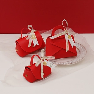 Three red leather wedding favor bags in handbag style with beige ribbons and gold charms