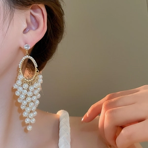 Close-up of elegant pearl grape cluster earrings with tassels on model ear