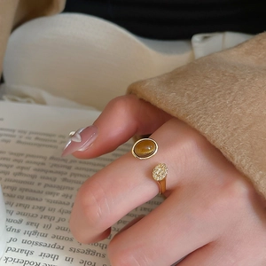 Detail of adjustable open ring featuring oval brown stone and gold-plated textured metal