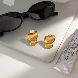 Classic gold egg-shaped stainless steel earrings with zircon stone on laptop background