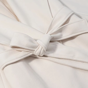 Close-up detail of the cream wool coat featuring a soft waist tie and delicate texture