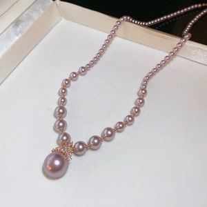 Détail de collier en perles roses avec pendentif en cristal et boîte blanche