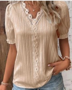 Detail of V-neckline with delicate white lace trim on champagne pleated fabric