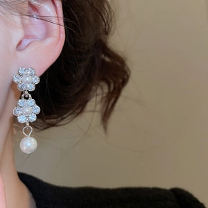 Detail of silver flower earrings with small pearls and crystals on a model's ear